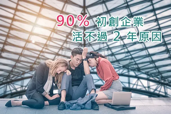 Three young professionals sitting dejected on the floor under a glass roof, with a laptop beside them